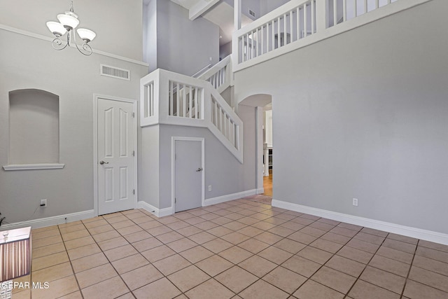 interior space featuring a towering ceiling, an inviting chandelier, and tile patterned flooring