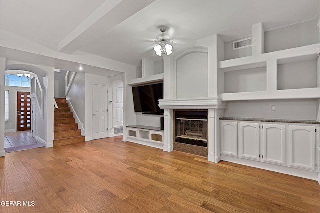 unfurnished living room with a large fireplace, ceiling fan, and light hardwood / wood-style flooring