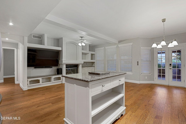 kitchen with hardwood / wood-style flooring, hanging light fixtures, a center island, white cabinetry, and ceiling fan with notable chandelier