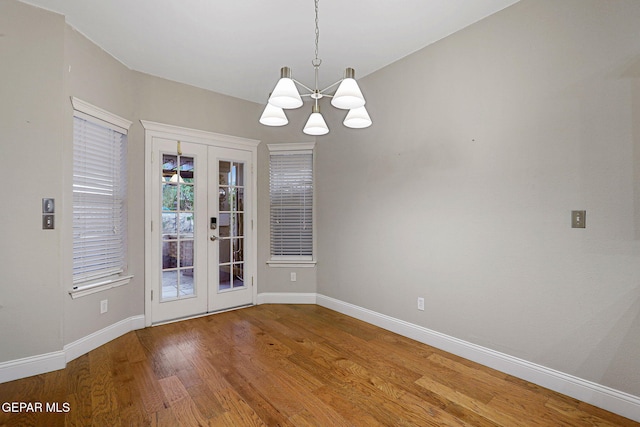 empty room with an inviting chandelier, french doors, and hardwood / wood-style floors