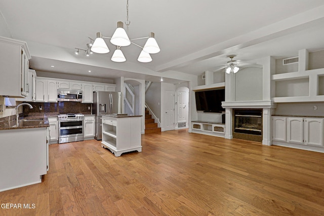 kitchen with white cabinetry, light hardwood / wood-style floors, stainless steel appliances, pendant lighting, and decorative backsplash