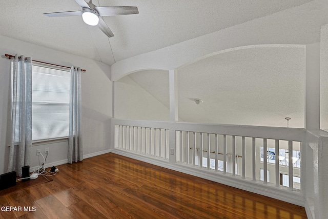 empty room with ceiling fan, a textured ceiling, lofted ceiling, and dark hardwood / wood-style floors