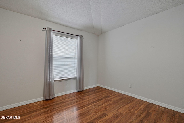 empty room with a textured ceiling and dark hardwood / wood-style floors