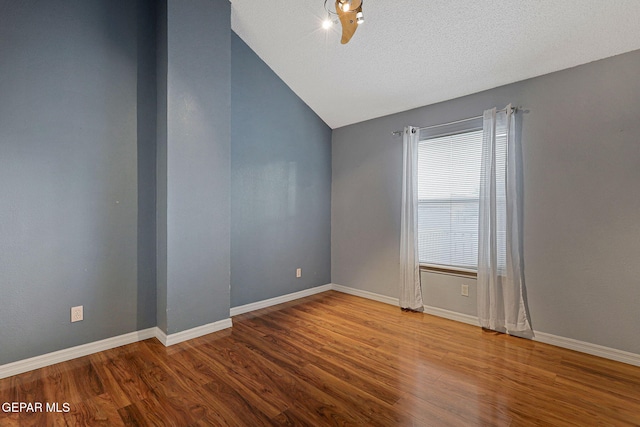 spare room featuring lofted ceiling, a textured ceiling, and wood-type flooring