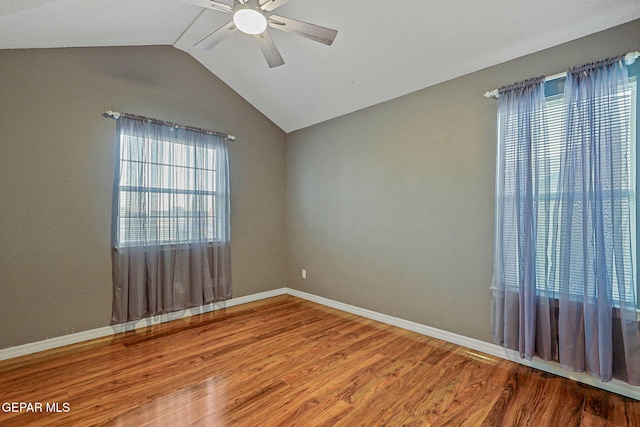 spare room featuring hardwood / wood-style floors, vaulted ceiling, and a healthy amount of sunlight