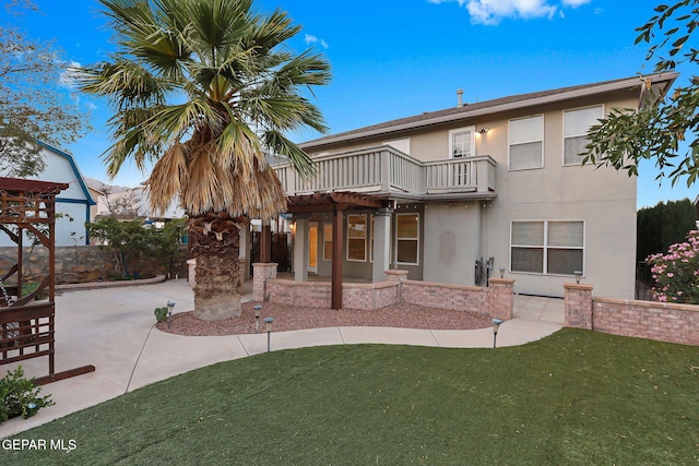 view of front of property featuring a patio area, a front lawn, a pergola, and a balcony