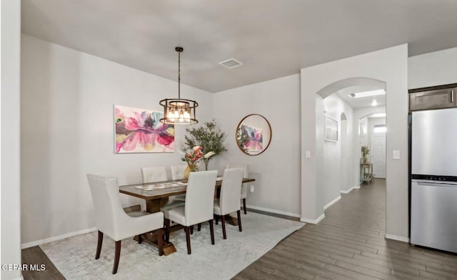 dining area with dark wood-type flooring and a notable chandelier