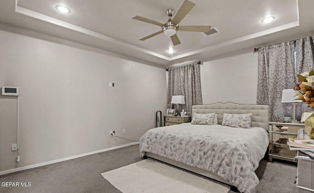 bedroom with a raised ceiling, ceiling fan, and carpet floors