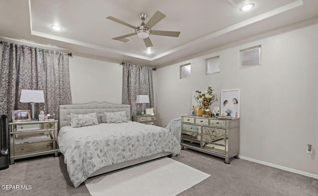 carpeted bedroom featuring a raised ceiling and ceiling fan