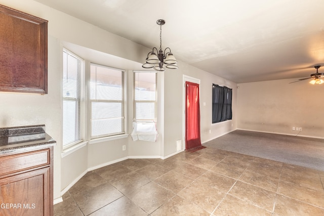 unfurnished dining area featuring light tile patterned flooring and ceiling fan with notable chandelier