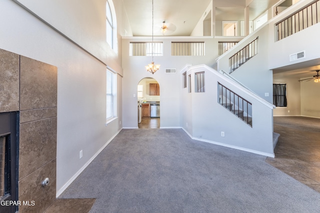 unfurnished living room with ceiling fan, high vaulted ceiling, and dark colored carpet