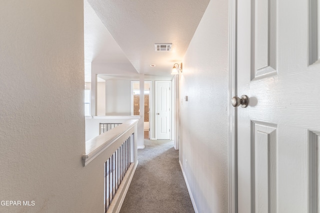 hallway featuring a textured ceiling and carpet flooring