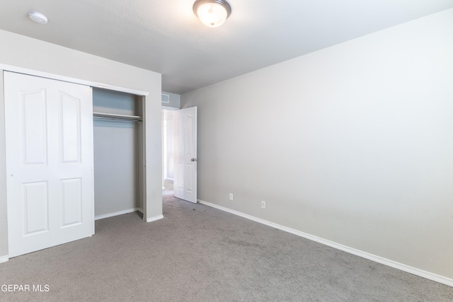 unfurnished bedroom featuring light carpet and a closet