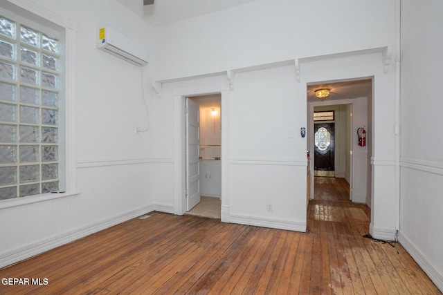 spare room featuring an AC wall unit and hardwood / wood-style flooring