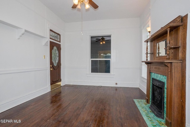 unfurnished living room featuring ceiling fan, a fireplace, and dark hardwood / wood-style floors