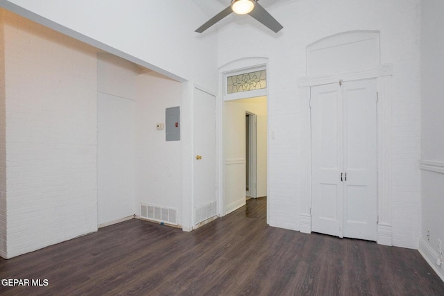 unfurnished room featuring ceiling fan, brick wall, dark hardwood / wood-style flooring, and electric panel