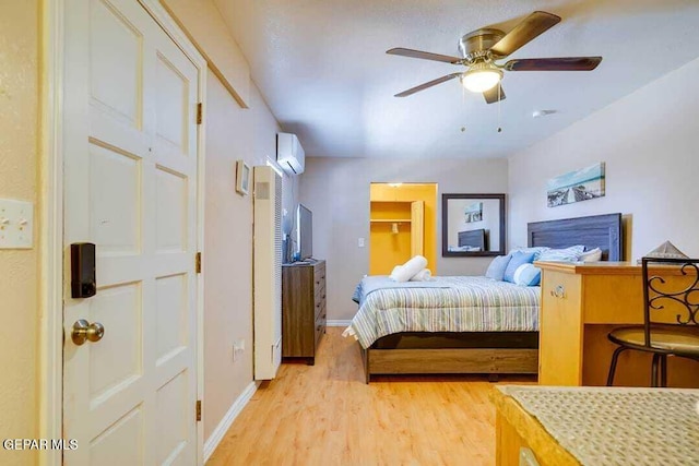 bedroom with light hardwood / wood-style floors, an AC wall unit, and ceiling fan