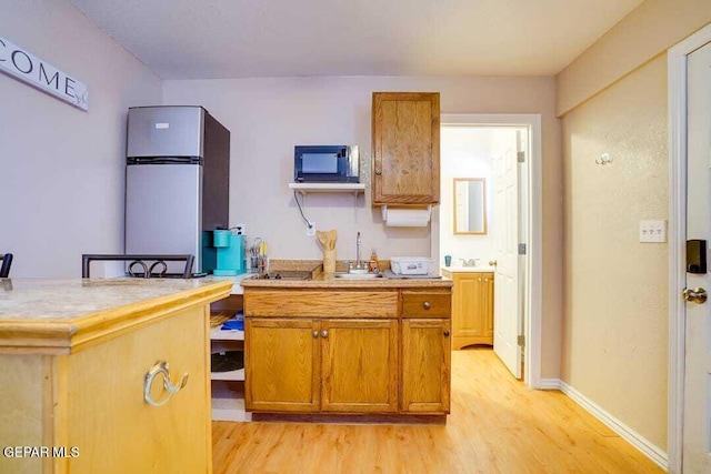 kitchen featuring stainless steel fridge, light hardwood / wood-style flooring, and sink