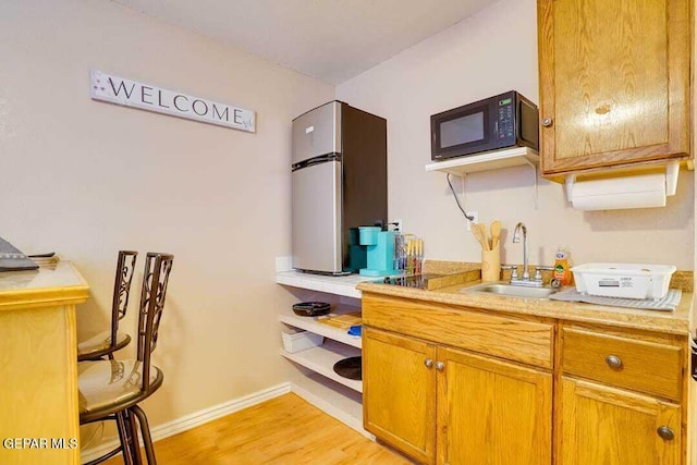 kitchen featuring stainless steel fridge, sink, and light hardwood / wood-style flooring