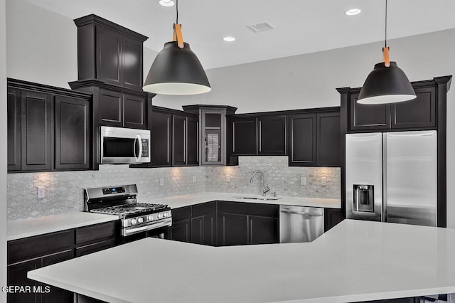 kitchen featuring sink, appliances with stainless steel finishes, decorative backsplash, and pendant lighting