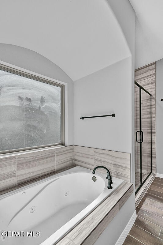 bathroom with independent shower and bath, vaulted ceiling, and wood-type flooring