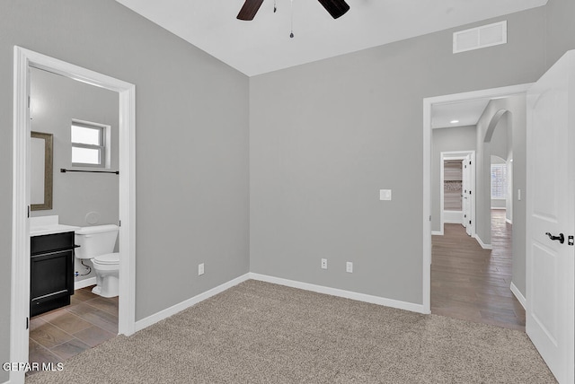 unfurnished bedroom with ensuite bath, light wood-type flooring, and ceiling fan