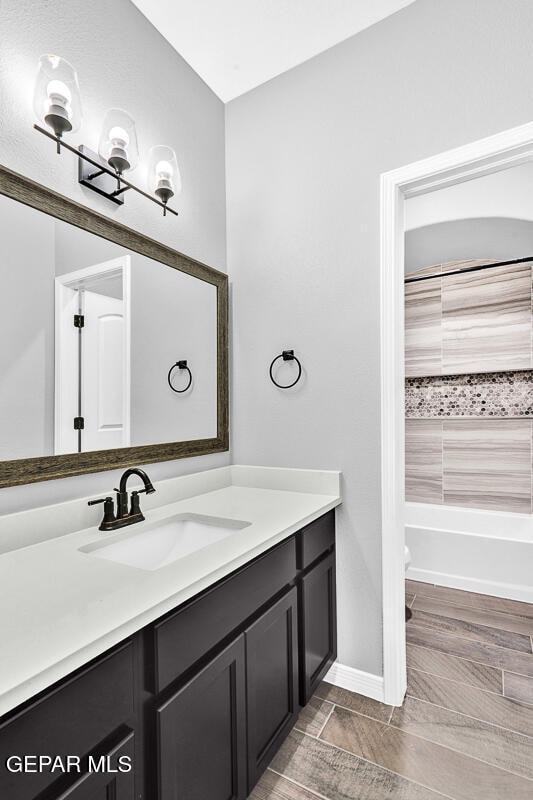 bathroom with vanity, hardwood / wood-style floors, and a tub to relax in