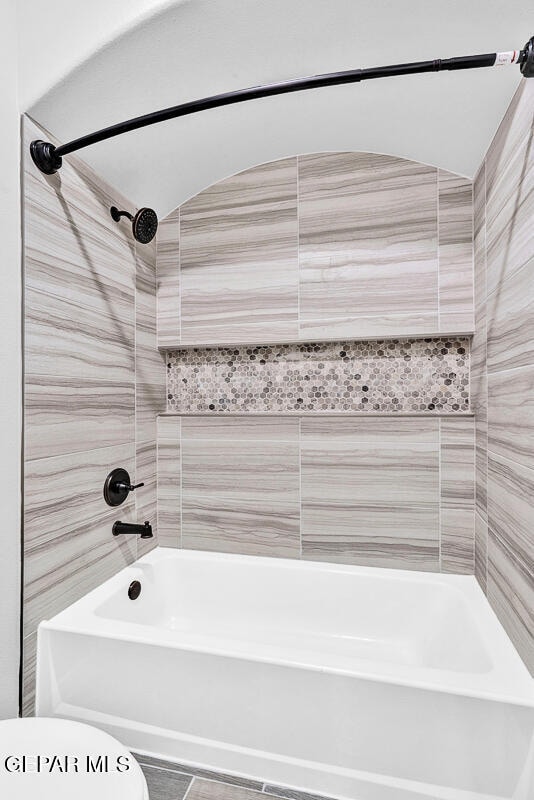 bathroom with toilet, tile patterned floors, and tiled shower / bath