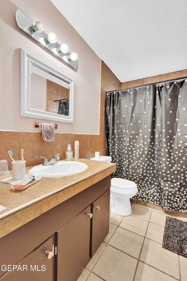 bathroom featuring a shower with shower curtain, vanity, tile walls, tile patterned flooring, and toilet