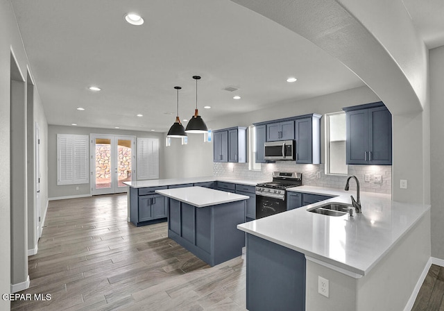 kitchen with appliances with stainless steel finishes, kitchen peninsula, sink, and light hardwood / wood-style flooring