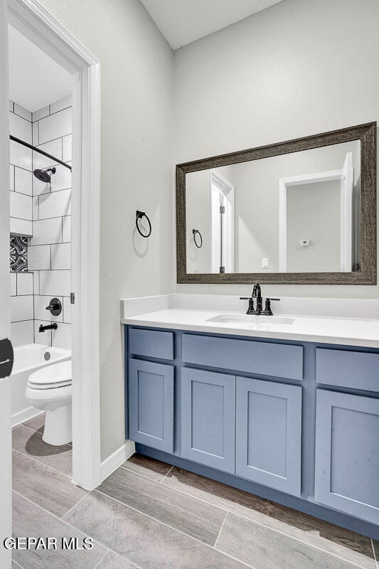 full bathroom with vanity, tiled shower / bath, and toilet