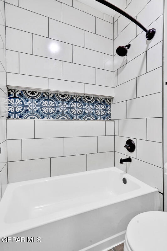 bathroom with toilet and tiled shower / bath