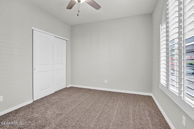 unfurnished bedroom featuring multiple windows, ceiling fan, a closet, and carpet