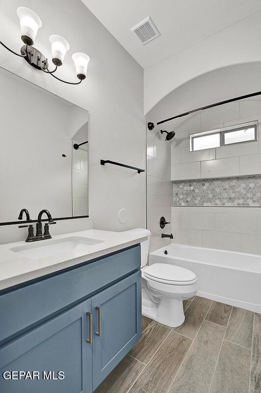 full bathroom featuring toilet, vanity, and tiled shower / bath