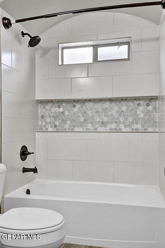 bathroom featuring tiled shower / bath combo and toilet