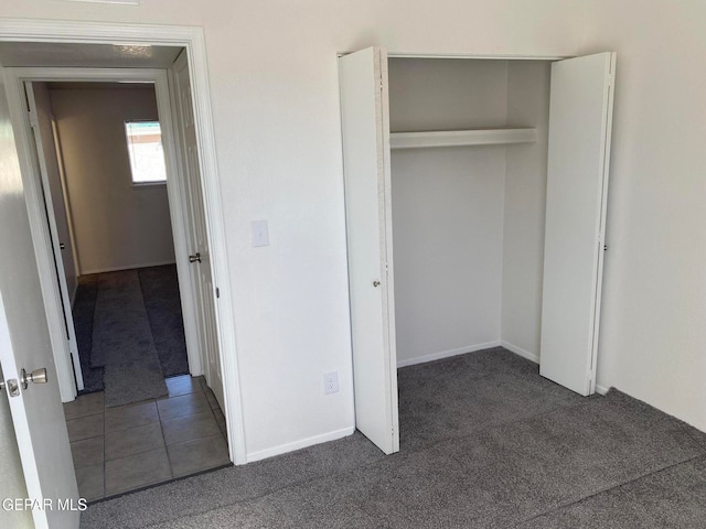 unfurnished bedroom with dark colored carpet and a closet