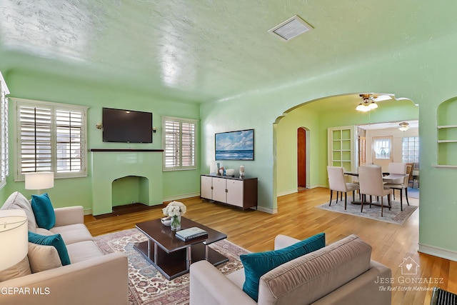 living room featuring a textured ceiling, ceiling fan, and light hardwood / wood-style flooring