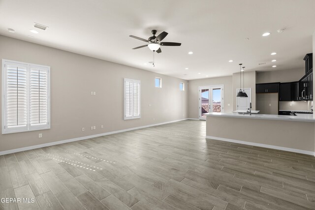 unfurnished living room featuring sink, dark wood-type flooring, french doors, and ceiling fan