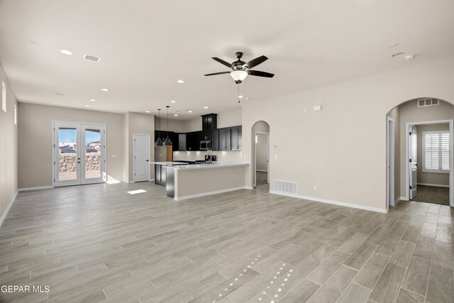 unfurnished living room with french doors, ceiling fan, and light wood-type flooring