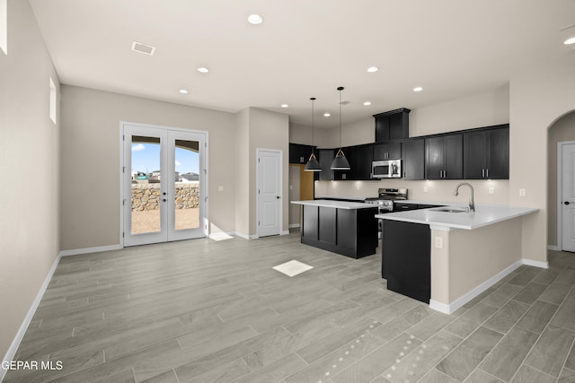 kitchen featuring french doors, kitchen peninsula, stainless steel appliances, decorative light fixtures, and light hardwood / wood-style floors