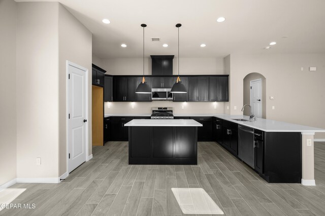 kitchen with sink, appliances with stainless steel finishes, decorative light fixtures, and a center island