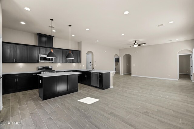 kitchen featuring light hardwood / wood-style floors, stainless steel appliances, decorative light fixtures, and a kitchen island