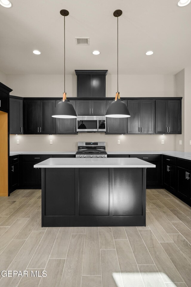 kitchen featuring pendant lighting, a center island, stainless steel appliances, and light wood-type flooring