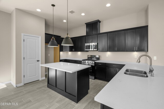 kitchen featuring stainless steel appliances, sink, a center island, decorative light fixtures, and light hardwood / wood-style floors