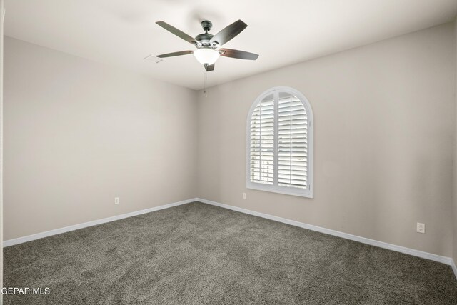 spare room featuring ceiling fan and dark colored carpet