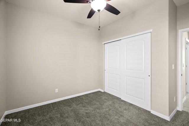 unfurnished bedroom with a closet, ceiling fan, and dark colored carpet