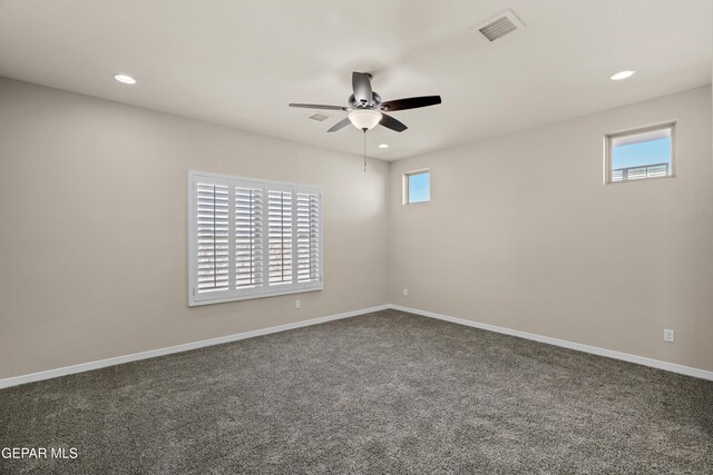 spare room with ceiling fan and dark colored carpet