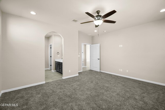 unfurnished bedroom with ensuite bath, light carpet, and ceiling fan