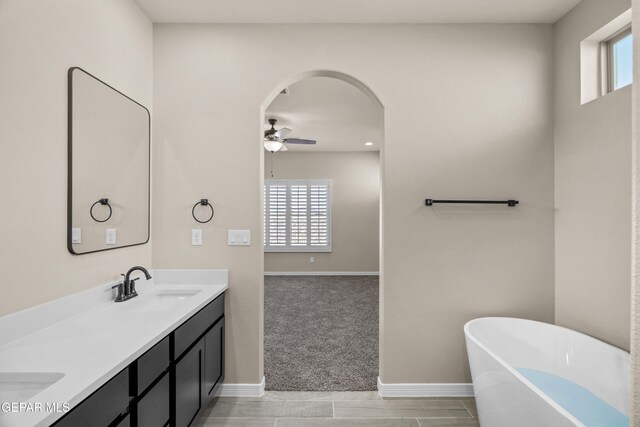 bathroom featuring vanity, a tub to relax in, a wealth of natural light, and ceiling fan