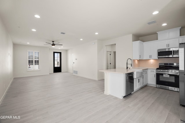 kitchen with white cabinetry, light hardwood / wood-style floors, stainless steel appliances, and kitchen peninsula